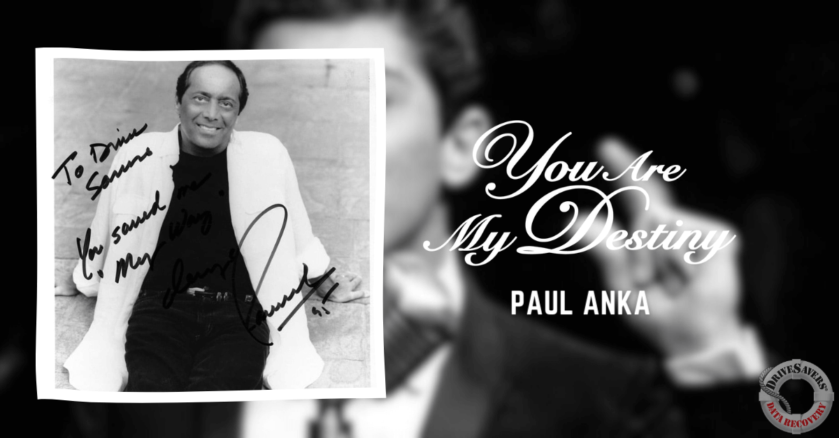 The black and white album cover for "You Are My Destiny" by Paul Anka features a classic, timeless design. At the center is a signed photo of Paul Anka, captured mid-smile, radiating a warm and charismatic presence. The inscription beside the photograph reads: "To Diane Summers, You sound as great as you look." The backdrop is simple yet elegant, allowing the focus to remain entirely on Anka's image and his personal message. This cover exudes a vintage charm that complements the nostalgic feel of his music.