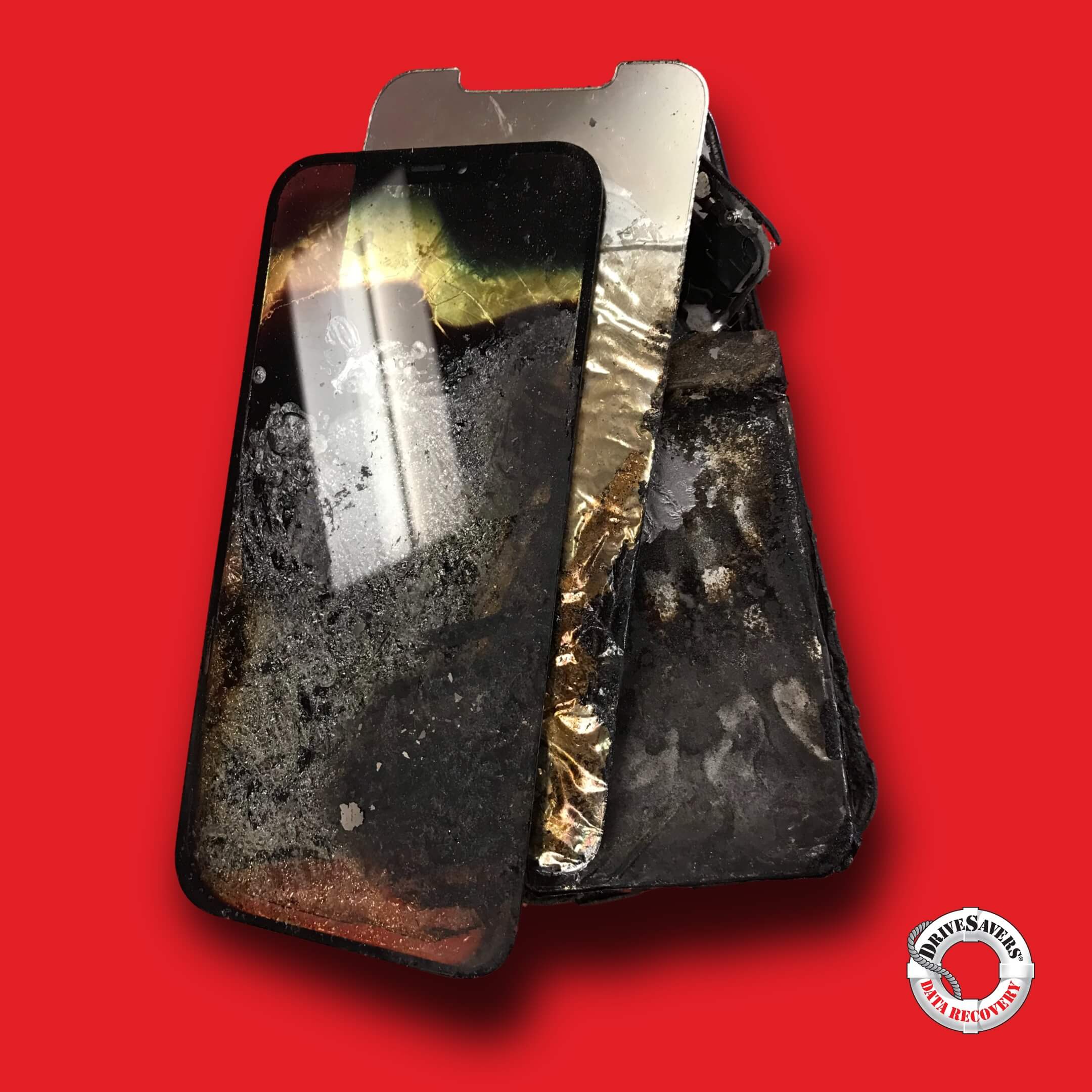 Un smartphone gravement endommagé avec un écran brisé et des composants brûlés sur un fond rouge. Un logo circulaire avec du texte se trouve dans le coin inférieur droit.
