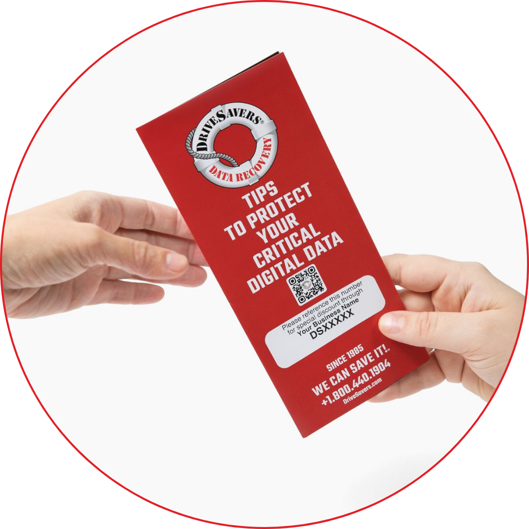 Deux mains échangent une brochure rouge intitulée "Tips to Protect Your Critical Digital Data" par DriveSavers Data Recovery. La brochure comporte un code QR et les coordonnées d'un contact en bas de page.